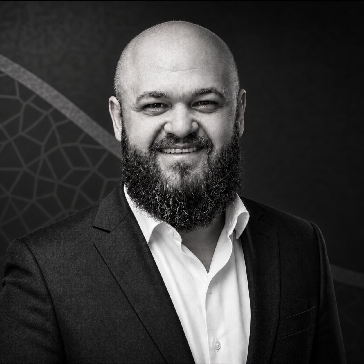 Mahdi Ajaj smiling in a suit, black-and-white portrait